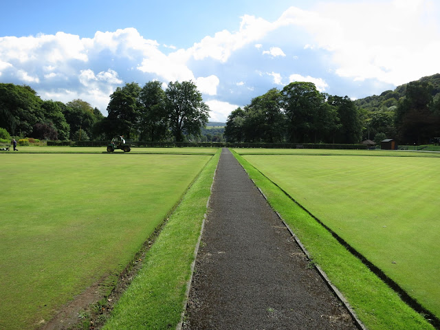 Path between bowling greens with park-keepers mowing the grass in Todmorden, West Yorkshire