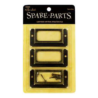 http://www.hobbylobby.com/Scrapbook-%26-Paper-Crafts/Embellishments/Trinkets/Antique-Gold-Label-Holders-with-Brads/p/20006