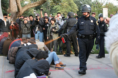 Policeman spraying seated, non-resisting protestors in face with pepper spray