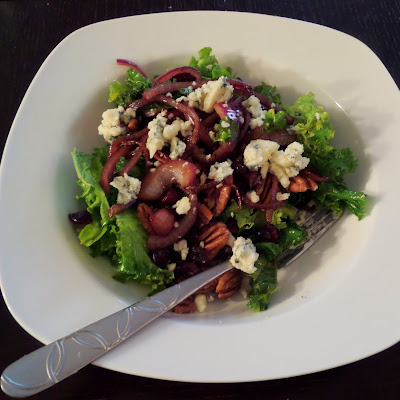 Warm Kale Salad:  A salad made of red onions sauteed in oil and balsamic vinegar mixed with kale and topped with blue cheese, toasted pecans, and dried cranberries.