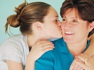 A young teenage girl kissing her mum on the cheek. A young teenage girl kissing her mum on the cheek.