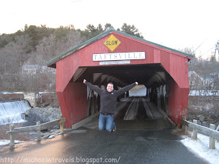 a man jumping in front of a red covered bridge