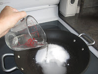 Pouring water onto sugar into a pan on the stove