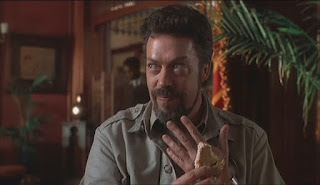 Tim Curry as Herkemer Homolka in Congo sesame cake