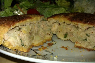 Homemade salmon fishcakes cut in half to show the filling and served with a fresh salad.