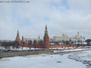 a large brick wall with towers and a river in front