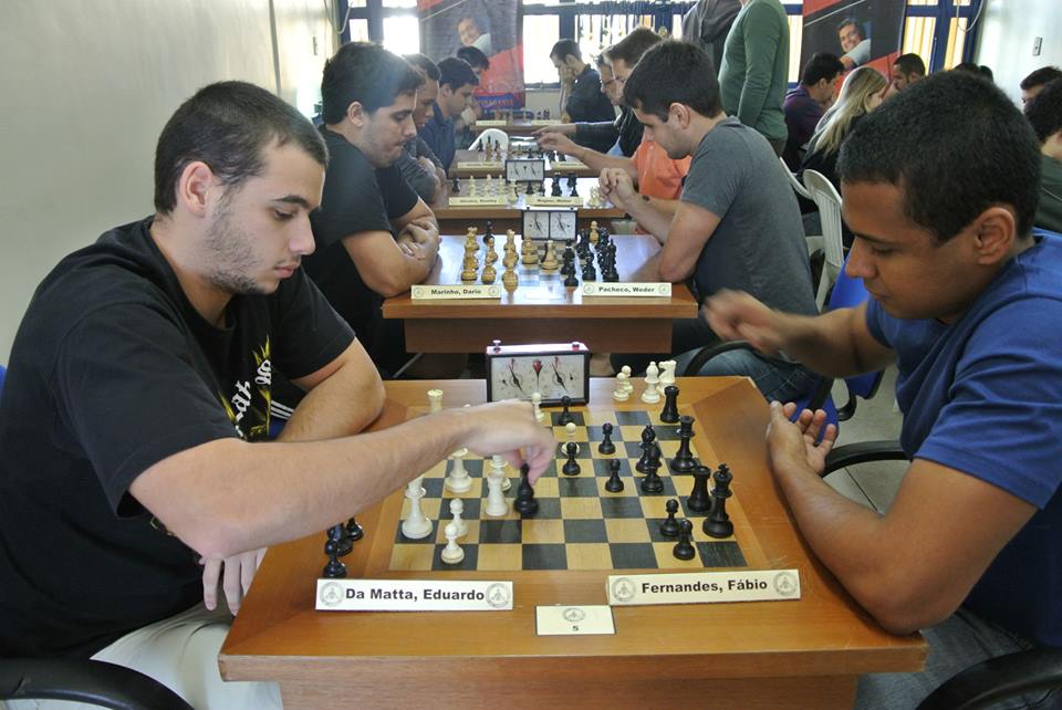 Os jogadores de xadrez masculinos começam a jogar, o primeiro movimento.  dois jogadores de xadrez começam o torneio intelectual dentro de casa.  tabuleiro de xadrez na mesa de madeira, jogo de estratégia