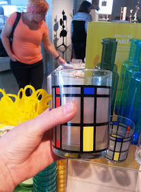 A hand holding a Piet Mondrian-styled glass in a gift shop.