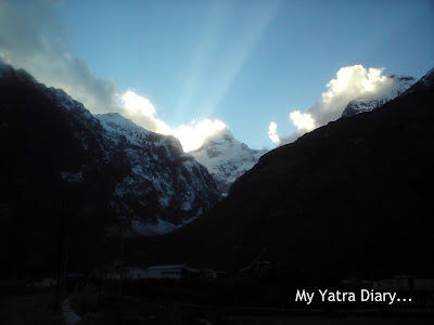 Sun peeping out from behind the clouds just before sunset  in the Garhwal Himalayas