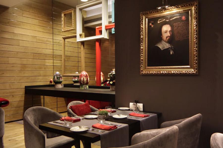 Picture of black square dining table by the wall with William Shakespeare picture on it