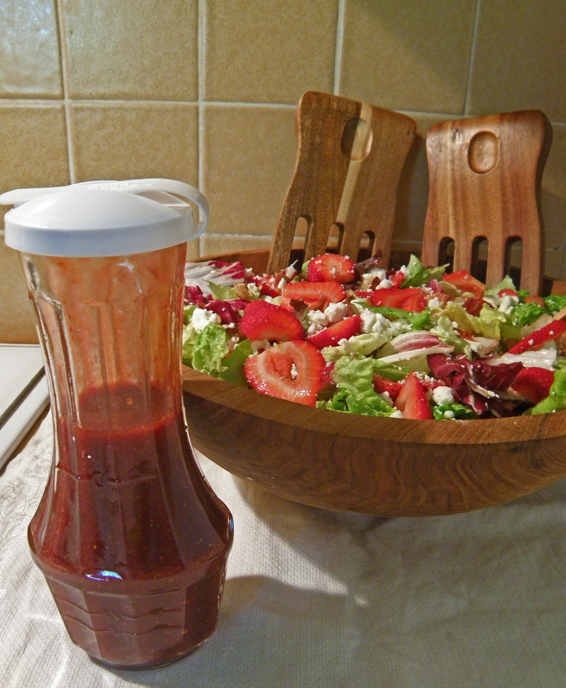 Strawberry Salad in Wooden Bowl with Tongs and Bottle of Strawberry Dressing