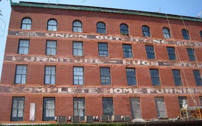 Brick warehouse with faded letters of a 19th century sign running between the windows of all the floors