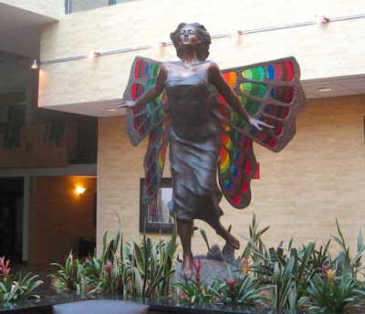 Bronze statue of a running girl with huge butterfly wings in rainbow stained glass