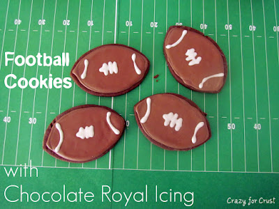 Football cookies with chocolate royal icing on a green faux background of a football field