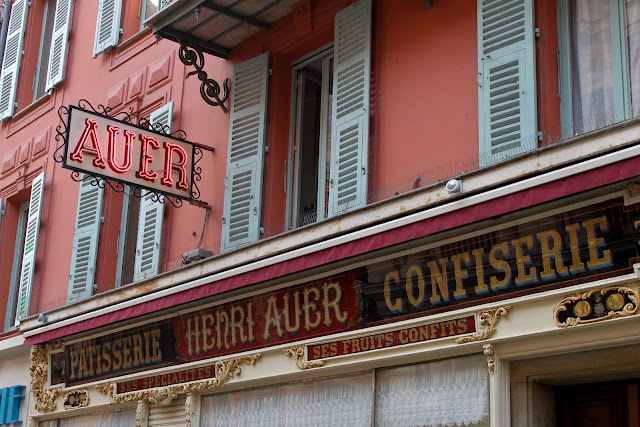 Terracotta washed walls, sea green painted wooden shutters and gold glass lettering in a patisserie.