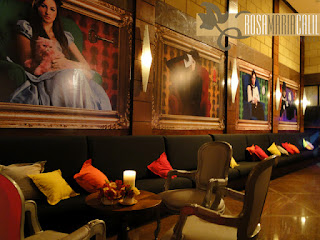 Espaço Jovem sofá preto, almofadas coloridas, quadros, poltrona Luis XV