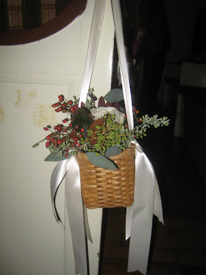 The pew decorations were little baskets filled with greenery and white roses