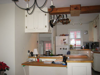 Kitchen before remodeling with a hanging pot rack and chandelier that made the room cluttered
