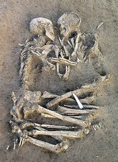 Dos esqueletos, están entrelazados uno frente a otro, desenterrados