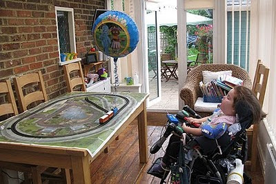 Image of Sophie Patmore using her switch adapted Thomas the Tank Engine set. A large helium balloon is tied to the train to make it more fun to use.