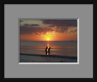 children silhouetted playing on a beach at sunset