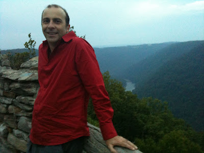 a man standing on a rock ledge with a view of a river and trees