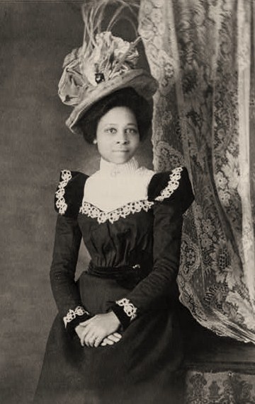 Young+African+American+woman,+three-quarter+length+portrait,+facing+slightly+right,+with+hands+folded+on+her+lap.jpg