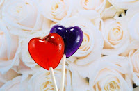 red and purple heart-shaped lollipops in front of roses