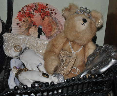 A mink teddy surrounded by vintage purses and gloves