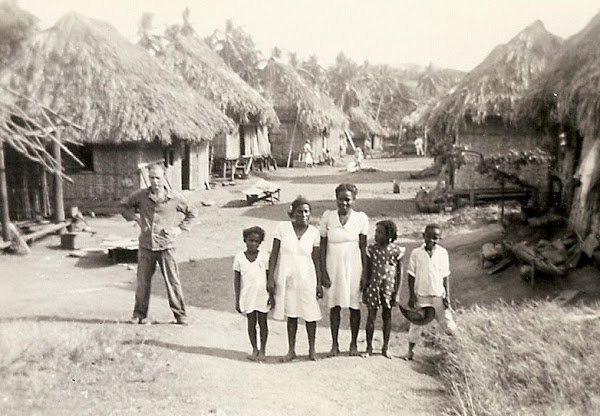 John standing by village huts.