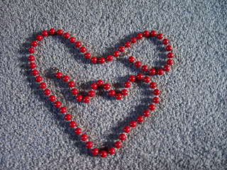 Macro red beads in shape of heart on green carpet