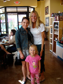 Two women and young girl standing in coffee shop smiling