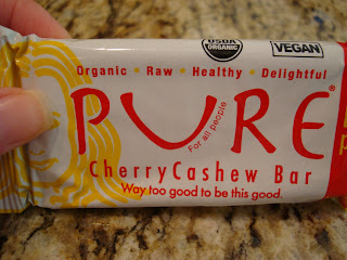 Hand holding Pure Cherry Cashew Bar in package