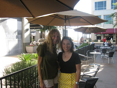 Two woman standing on outdoor patio under umbrella