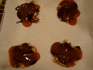 Chocolate covered pecan piles drizzled with caramel sauce on parchment paper