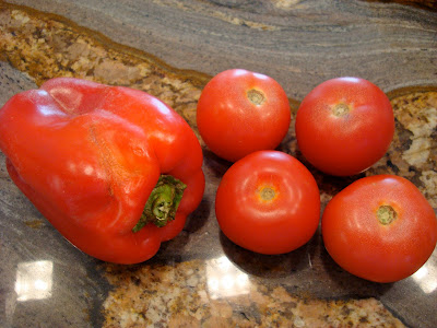 Four tomatoes and one red pepper on countertop