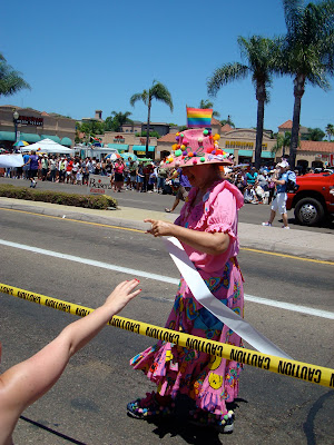 Person in pink dress and pink floppy hat walking down street
