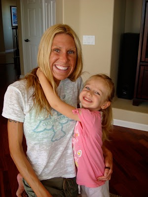 Child with arms around woman's neck smiling
