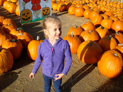 Young girl standing by rows of pumpkins