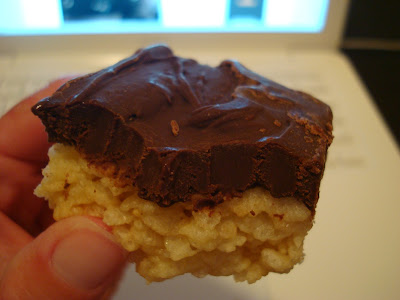 Close up of hand holding one GF Vegan "Rice Krispie" Treat with Chocolate Peanut Butter Coconut Oil Frosting 