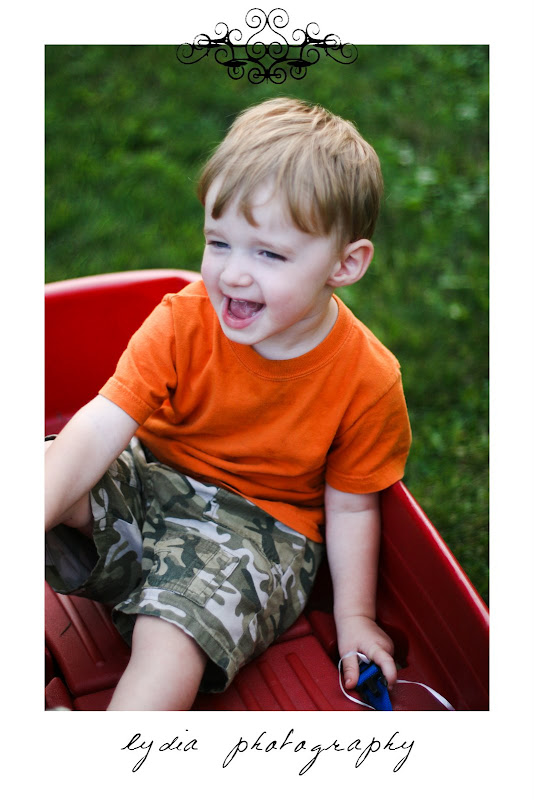 Little boy laughing in the red wagon at lifestyle kids portraits on a farm in Indiana, Pennsylvania