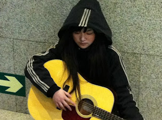 乞丐蘿莉 坐在冰冷的地上抱著吉他，手指都已經凍的泛紅。」