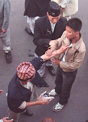Darjeeling Municipal Vice Chairman holds a young man as the other smears his face with oil paint