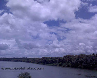 clouds floating on the sky photographed from a train moving through a bridge over the river 