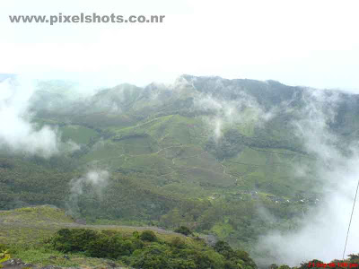 mist in munnar,mountain valleys getting covered in mist,moonar hill station photos,landscape photograph from munnar showing mist moving over mountains of munnar hillstation kerala