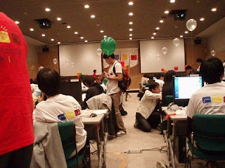 会議室でパソコンを使っている方や、他人と話している方の様子を示す画像。