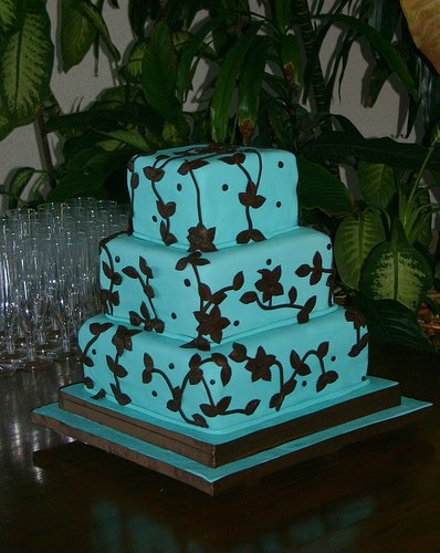 Three tier square wedding cake in blue with brown chocolate flower