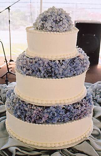 Three tier white round wedding cake with pale blue hydrangeas