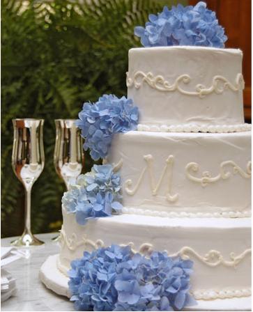Three tier white wedding cake with scroll texture and lovely blue hydrangeas 