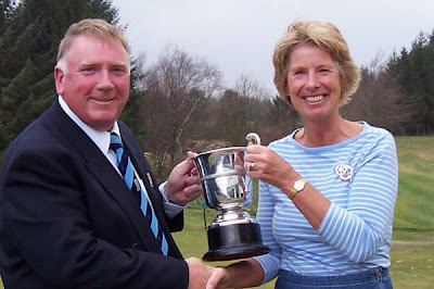Milngavie's Captain Anna Telfer receives the Centenary Trophy from Jimmy Graham Captain of Clober